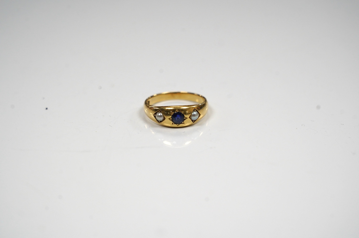 An early to mid 20th century 18ct and gypsy set single stone sapphire and two stone split pearl set ring, size O, gross weight 4.7grams. Condition - poor to fair